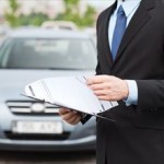 transportation and ownership concept - man with car documents outside